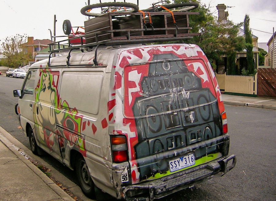 Old van with roof racks and graffiti.