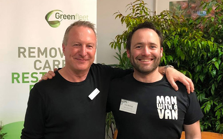 Two men standing in front of a tree with arms around each other's shoulders.