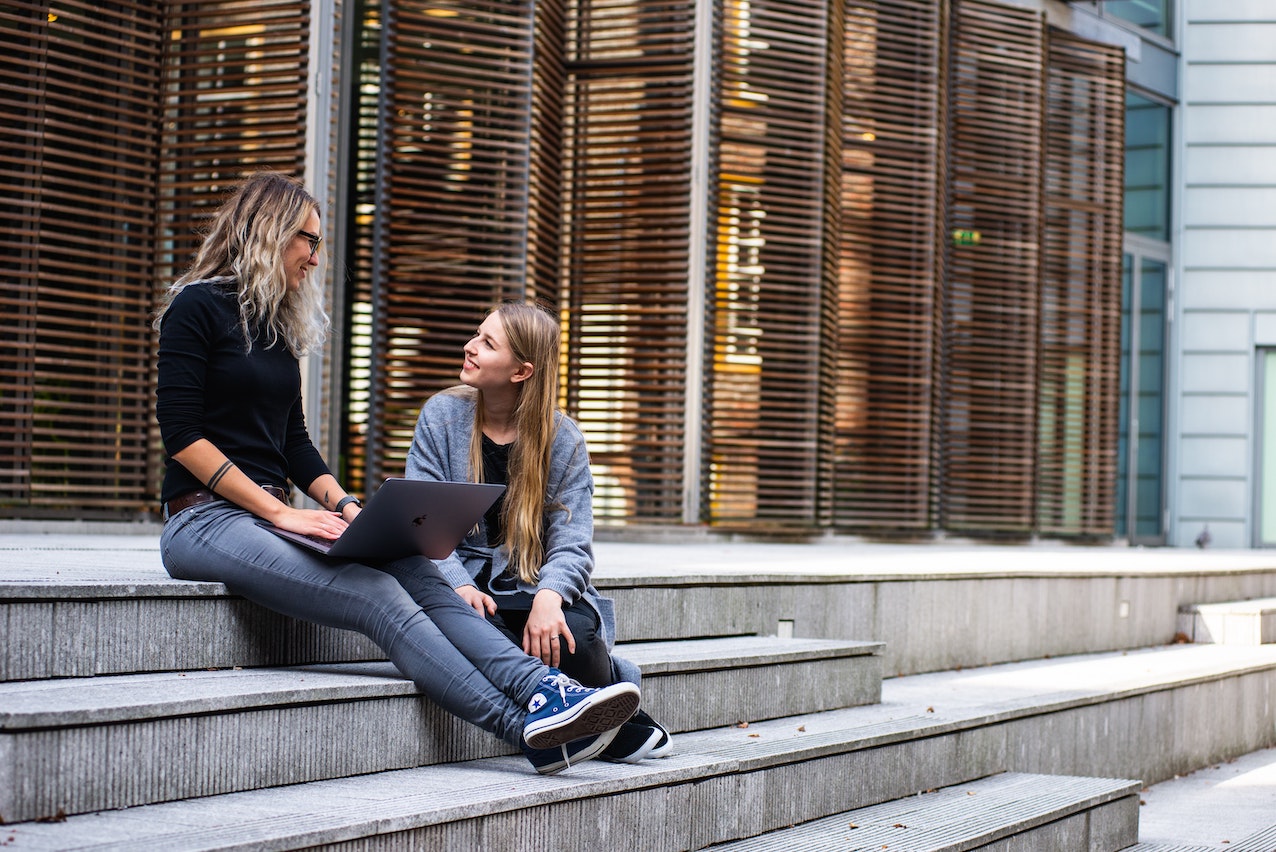 Students sitting on a step outside a university.